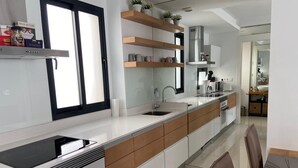 A modern kitchen with a large island, built-in appliances, and wooden accents.