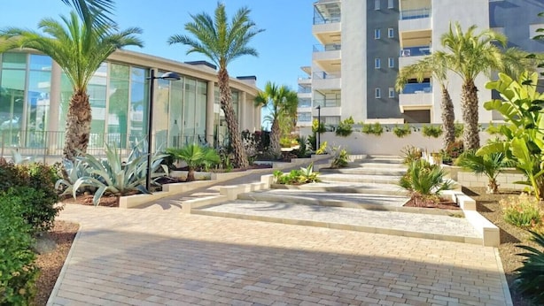 A modern building with a glass facade and a paved walkway. - Groundfloor GreenHills Villamartin, Orihuela Costa (Villamartín)