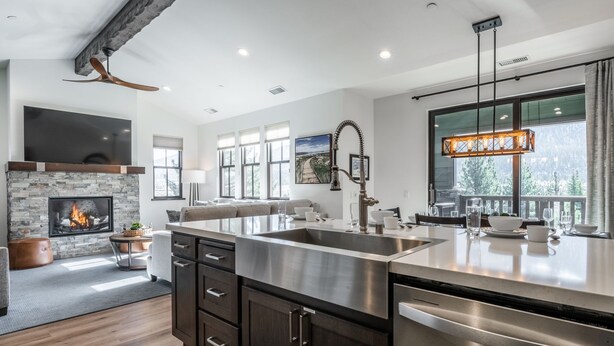 A modern kitchen with a central island, stainless steel appliances, and a stone fireplace.