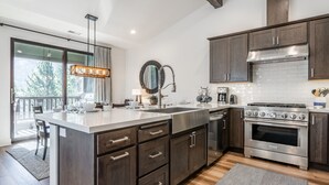 A modern kitchen with dark wood cabinets, stainless steel appliances, and a large island with a sink and countertop.