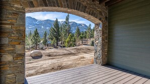 A stone archway leading to a wooden deck with a mountain view.