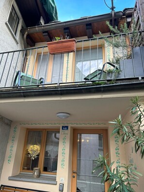 Un edificio de dos pisos con un balcón, una puerta con el número 4a y una ventana con una planta decorativa.