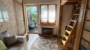 A cozy living room with a wooden ceiling, a sofa, a TV, and a staircase. - Casa Edera  (Locarno)
