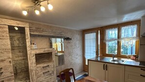 A kitchen with a wooden table, cabinets, a sink, and a ceiling light fixture. - Casa Edera  (Locarno)