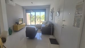 A room with a sofa, a small table, a cabinet, a floor lamp, and a sliding glass door leading to an outdoor area. - Penthouse Elisa Mil Palmeras (Torre de la Horadada)