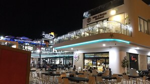 An outdoor dining area with tables and chairs, a restaurant with a sign for 'Indian & Mexican Restaurant', and a building with a sign for 'Plaza Nueva'. - Penthouse Higuericas Playa, Pilar de la horadada (Pilar de la Horadada)