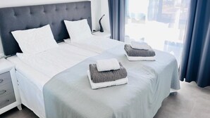 A hotel room with a large bed, two pillows, a bedside table with a lamp, and a view of the city through the window. - Penthouse Higuericas Playa, Pilar de la horadada (Pilar de la Horadada)