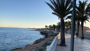 A coastal promenade with a paved walkway, palm trees, and a view of the sea. - Penthouse Higuericas Playa, Pilar de la horadada (Pilar de la Horadada)
