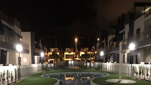A nighttime view of a swimming pool surrounded by well-lit buildings. - Penthouse Higuericas Playa, Pilar de la horadada (Pilar de la Horadada)