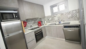 Une cuisine moderne dotée d’appareils électroménagers en acier inoxydable, d’un lave-vaisselle et de carreaux décoratifs sur le mur derrière l’évier ou la cuisinière.