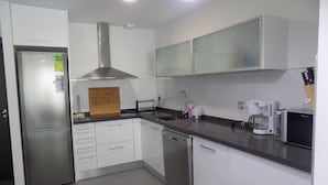 Una cucina moderna con mobili bianchi, elettrodomestici in acciaio inossidabile e un tagliere di legno.