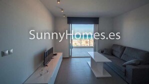 A modern living room with a flat-screen TV, a sofa, and a dining table. - Apartment Aqua nature La mata; costa Blanca (La Mata)