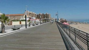 A boardwalk with a beach in the background, featuring a row of buildings with balconies and a clear sky. - Apartment Aqua nature La mata; costa Blanca (La Mata)