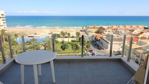 A balcony with a view of the beach, pool, and surrounding buildings. - Apartment Aqua nature La mata; costa Blanca (La Mata)