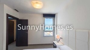 A bedroom with a bed, a nightstand, a window, and a door. - Apartment Aqua nature La mata; costa Blanca (La Mata)