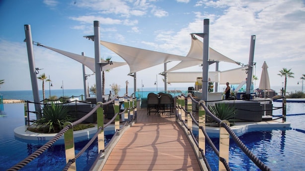 A wooden deck leading to a pool area with lounge chairs and umbrellas. - Groundfloor Sea Senses Punta Prima , Orihuela Costa (Torrevieja)