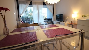 A dining area with a glass table, red placemats, and a vase with flowers. - Groundfloor Sea Senses Punta Prima , Orihuela Costa (Torrevieja)
