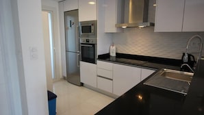 A modern kitchen with white cabinets, a black countertop, stainless steel appliances, and a black sink. - Groundfloor Sea Senses Punta Prima , Orihuela Costa (Torrevieja)