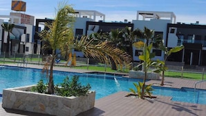 A swimming pool with a modern architectural backdrop, including a sign for 'DOLCE' and 'DOLCE & GABBANA'.