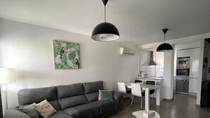 A modern living room with a grey sectional sofa, a round coffee table, and a dining area with a white table and chairs.