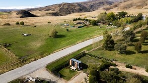 A rural landscape with a road, a small building, and scattered houses. - Ruffell Ranch Cabin by Tiny Away (Tarras)