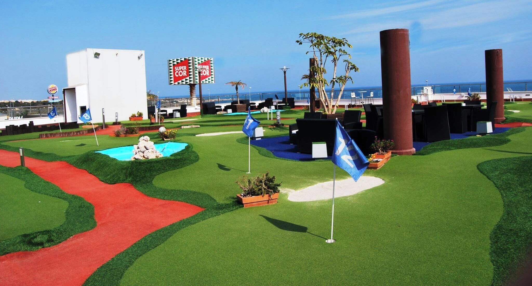 A miniature golf course with artificial grass, sand traps, and a water hazard.