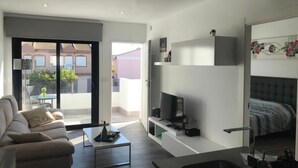 Una sala de estar moderna con sofá, mesa de centro, televisor y cama.