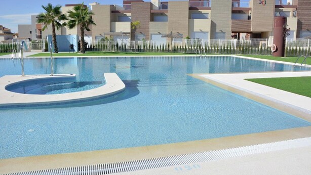 Ein Swimmingpool mit einer runden Whirlwanne, umgeben von einem Zaun und Palmen.