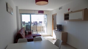 Ein modernes Wohnzimmer mit einem weißen Sofa, einem Esstisch und einem Fernseher auf einer Holzkommode.