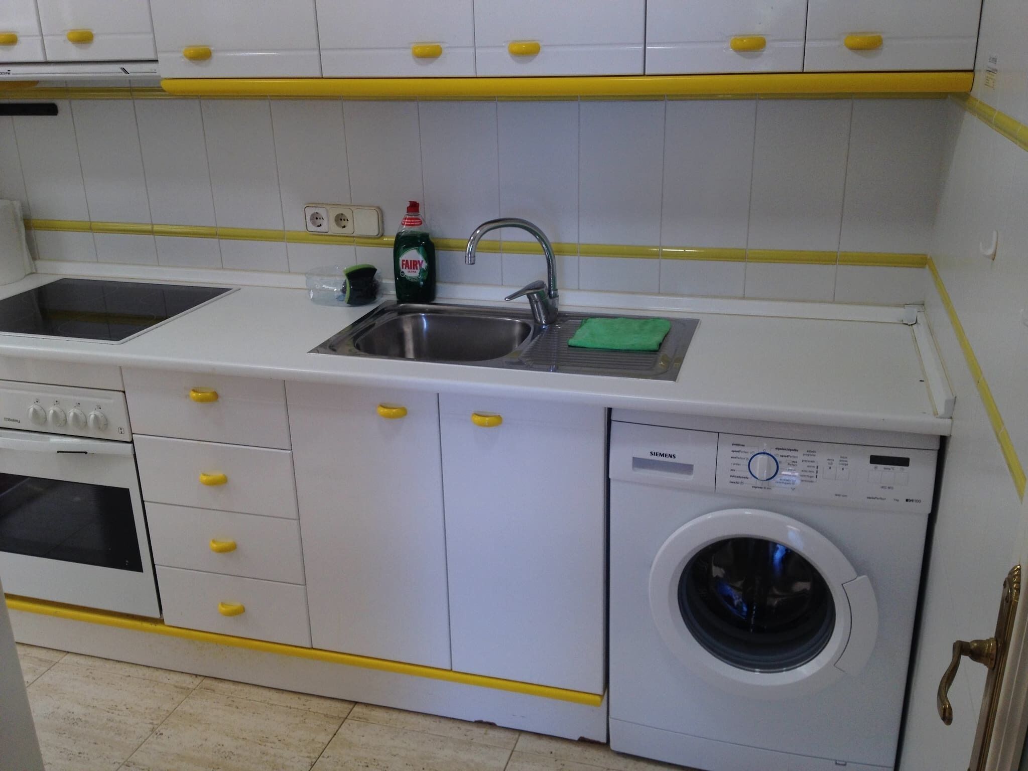 A kitchen with a washing machine, a sink, and a stove.