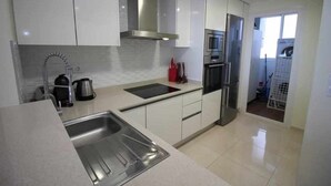 A modern kitchen with stainless steel appliances, white cabinetry, and a built-in oven. - Apartment Sea Senses Punta prima, Orihuela Costa (Torrevieja)