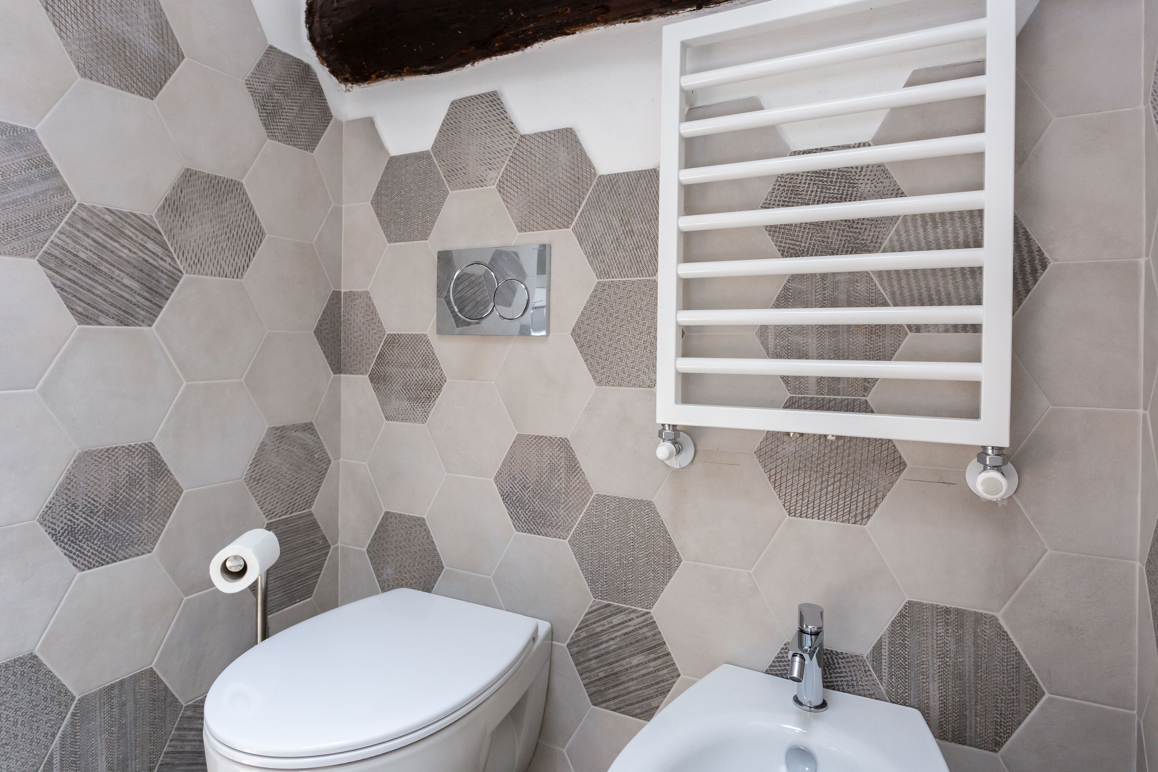 Ein Badezimmer mit sechseckigem Fliesenmuster, einer Toilette, einem Bidet und einem Handtuchhalter.