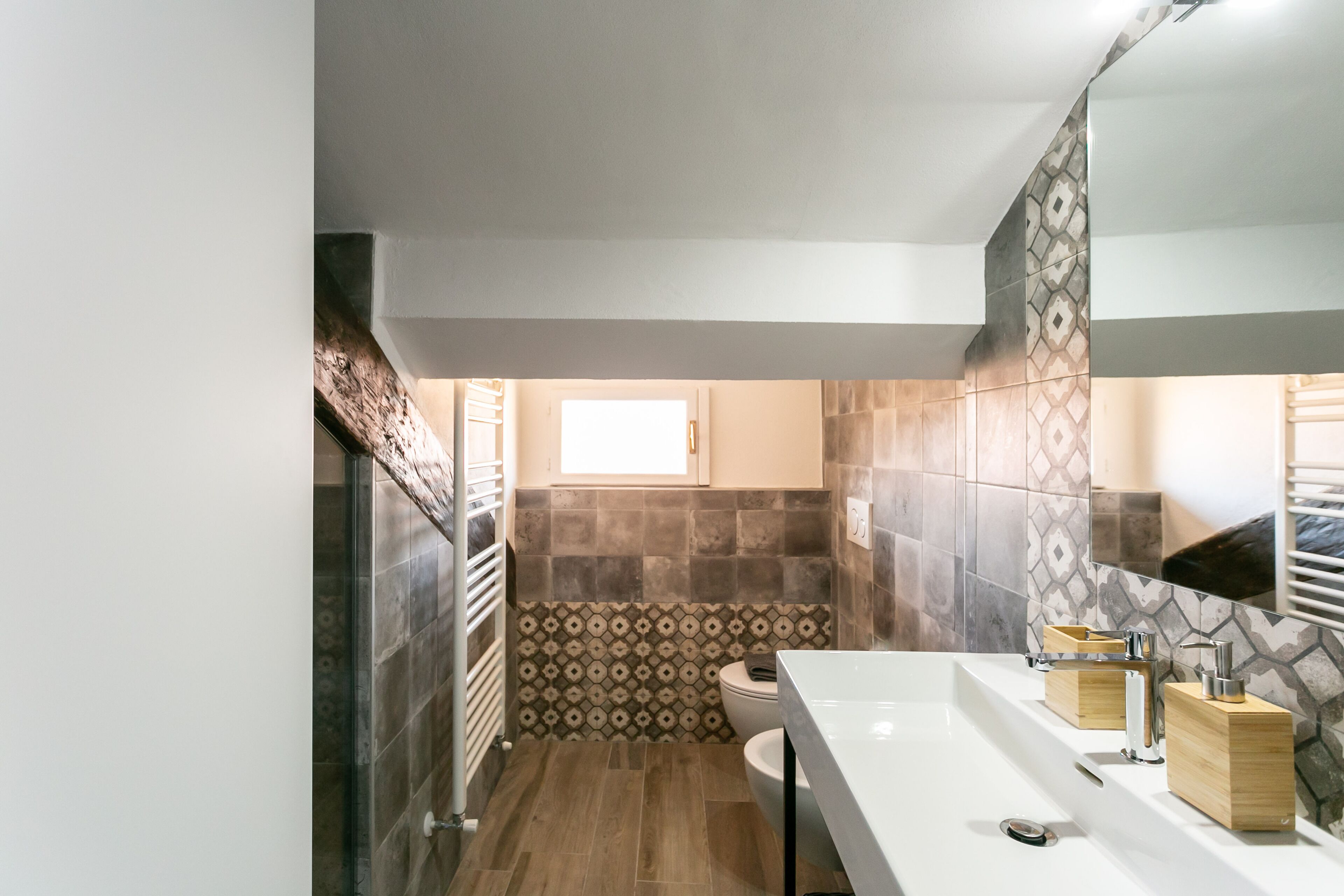 Een moderne badkamer met een wit wastafelmeubel, een spiegel en betegelde wanden.
