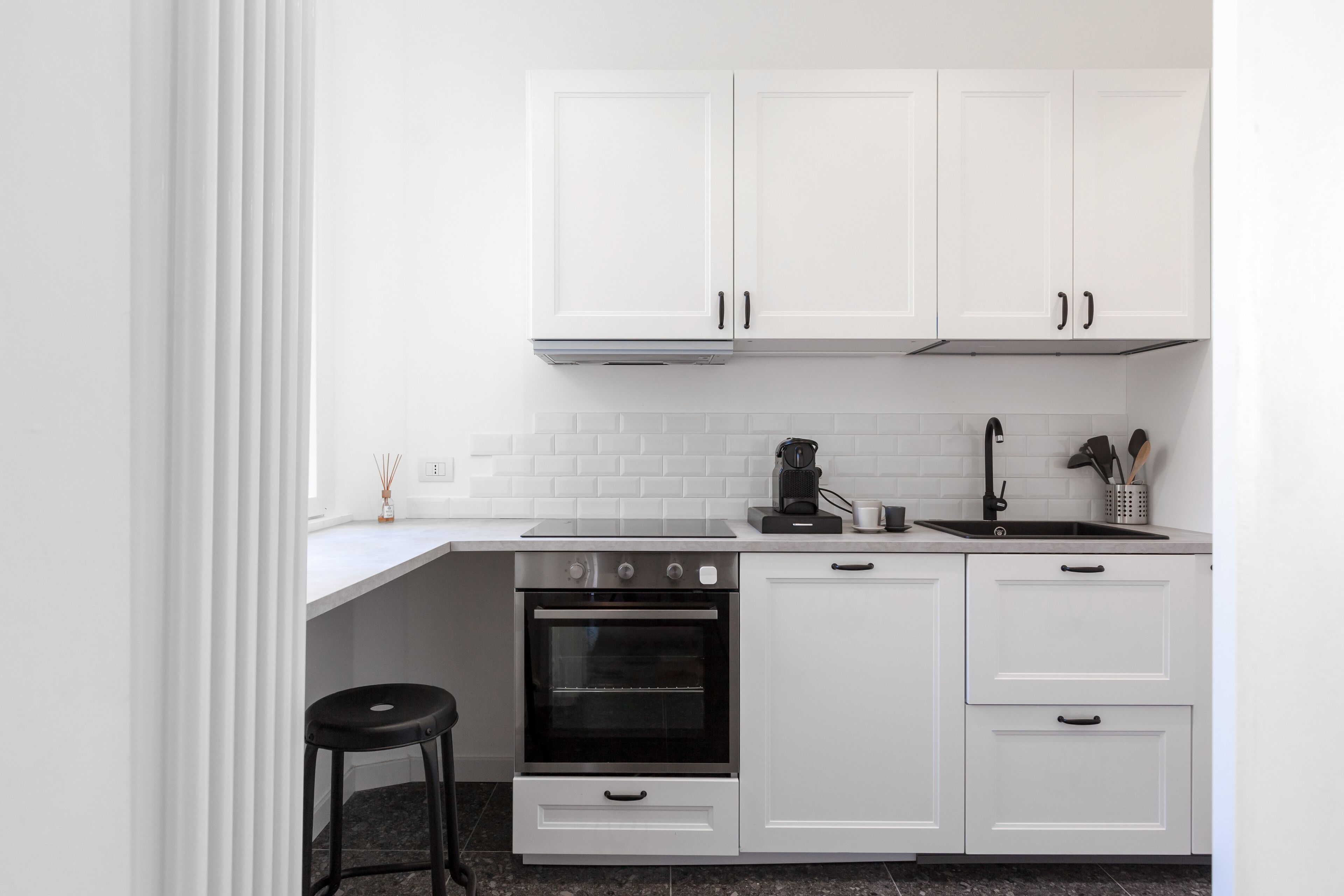 Een moderne keuken met witte kasten, een zwart aanrecht, een fornuis en een spoelbak.