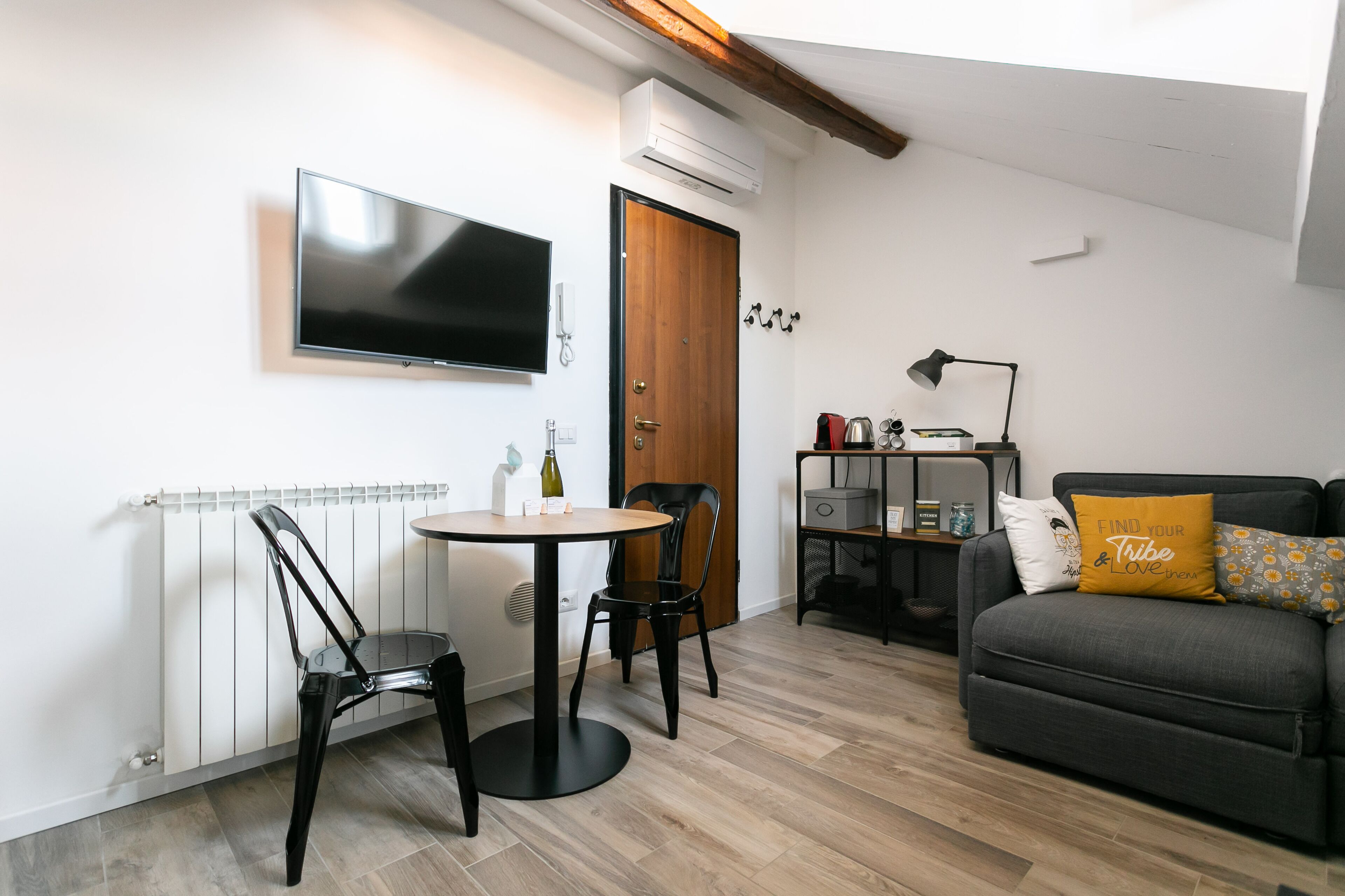 A compact living space with a dining area, a sofa, a TV, and a radiator.