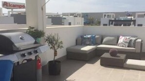 A rooftop patio with a grill, seating area, and a view of the cityscape. - Penthouse Oasis beach IV La zenia (La Zenia)