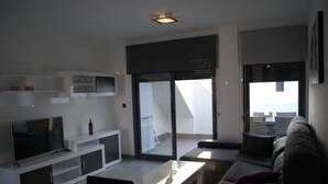 A modern living room with a flat-screen TV, a glass door leading to a balcony, and a sofa. - Penthouse Oasis beach IV La zenia (La Zenia)
