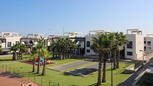 Ein moderner Gebäudekomplex mit mehreren weißen Bauten, Palmen und einem gepflegten Rasen.