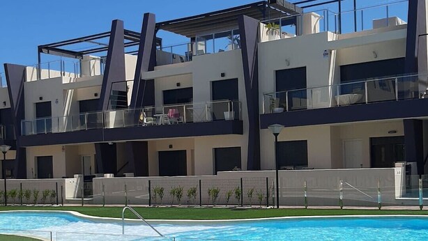 Ein modernes Hotel mit Swimmingpool, mehreren Balkonen und blauem Himmel.