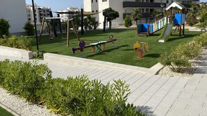 Een speeltuin met schommels, een glijbaan en een klimconstructie.