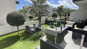 Een terras op het dak met buitenmeubilair, een glazen tafel en uitzicht op de skyline.