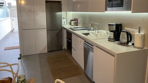 Een functionele keuken met een koelkast, magnetron, koffiezetapparaat en vaatwasser.