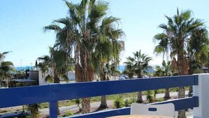 A balcony with a wooden table, surrounded by palm trees and a clear view of the sea. - Apartment Playa Flamenca  resd. Playa Terrazas (Orihuela Costa)