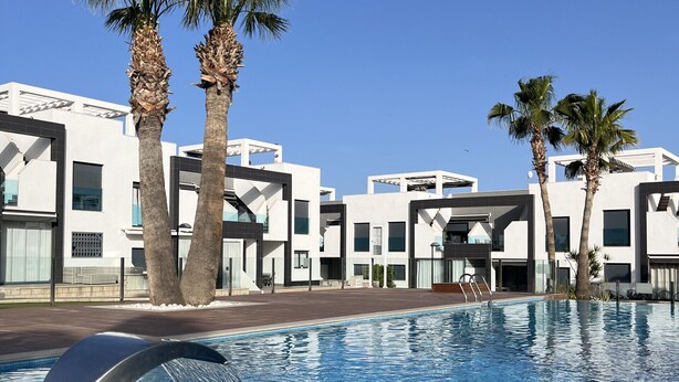 A swimming pool with a water feature, surrounded by modern buildings and palm trees. - Penthouse Oasis beach II La zenia (La Zenia)