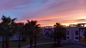 A modern building complex with a pool area, palm trees, and a sunset sky. - Penthouse Oasis beach II La zenia (La Zenia)