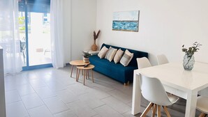 A modern living room with a blue sofa, a white dining table, and a small round table with a plant. - Ground floor Oasis Beach II La Zenia (La Zenia)