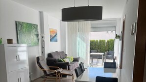 Une cuisine moderne avec un coin repas, comprenant un meuble blanc, un canapé gris et une table à manger avec des chaises.