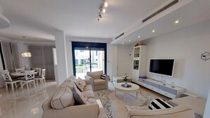 A modern living room with a sofa set, a dining table, and a TV.