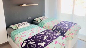 A bedroom with two beds, each with patterned bedding, a dark wall, and a window with curtains.