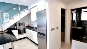 A modern kitchen with white cabinets, stainless steel appliances, and a black countertop. - Duplex private pool Sinergia Los Alcazares (Los Alcazares)